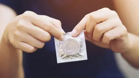 Getty Images Close up of hands holding a condom.