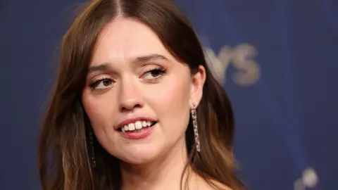 AFP A close up image of Aimee Lou Wood looking away from camera while smiling slightly as she's photographed on the red carpet at the Emmy's in LA on 14 September.