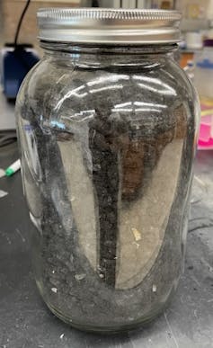 A jar containing biochar (charcoal) made from corn kernels.