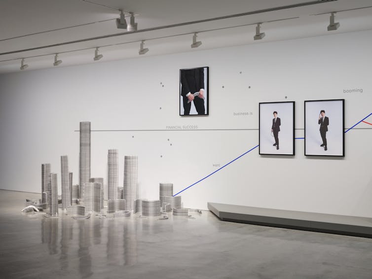 Stacked silver boomerangs, photographs of Williams in business suit mounted on a wall graph