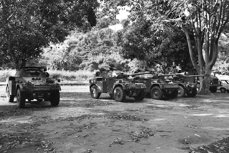 Tanks are positioned on a dirt road.