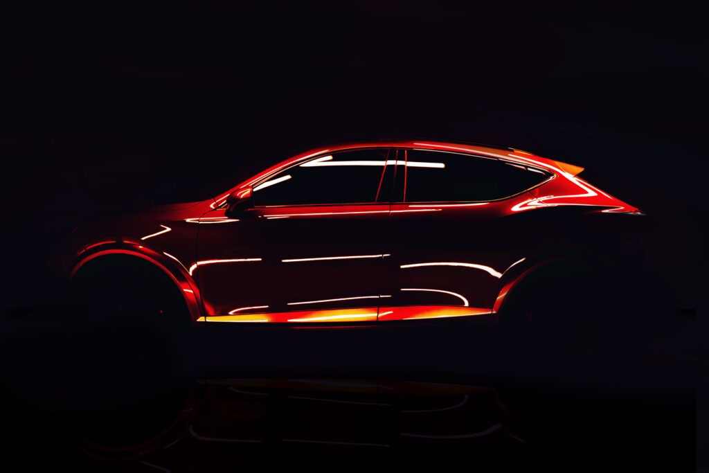 Futuristic red sports SUV illuminated by neon light in a dark studio.