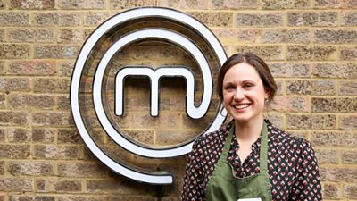 A portrait image of a contestant stood against an exposed brick wall, with the MasterChef circular white logo behind her.