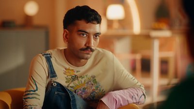 Image of Nabhaan Rizwan who plays Isaac, who can be seen looking at someone off camera and wearing dungarees