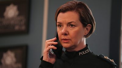 A headshot of a woman in police uniform holding a mobile phone up to her ear.