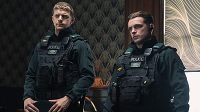 Two young men wearing policeman uniforms looking very serious 