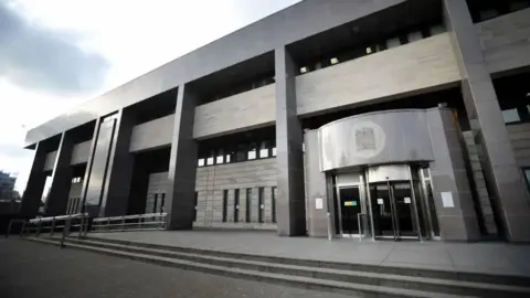 PA Media Glasgow Sheriff Court, an imposing late-Brutalist building with tall vertical columns in front and a curved structure over the glass doors. 