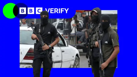 Getty Images Three Hamas fighters stand guard in Gaza. They are wearing balaclavas and armed with assault rifles. 