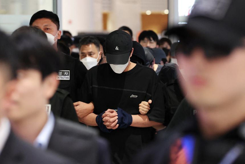 Police officers escort South Korean deportees suspected of being involved in online scam operations in Cambodia upon their arrival at the Incheon International Airport in Incheon, South Korea, October 18, 2025.
