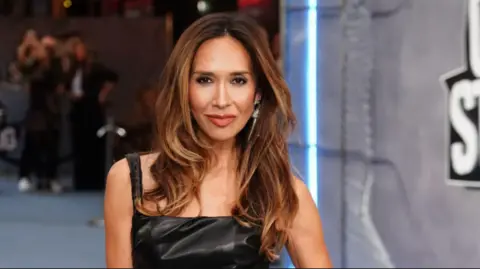 PA Media A woman with long brown hair is pictured wearing a black leather dress.
