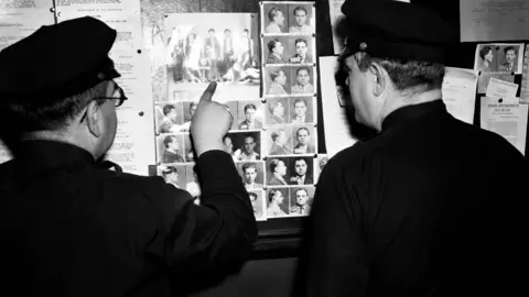 Getty Images Two Brooklyn police officers point at the line-up of members from the organised crime syndicate Murder Inc. circa 1940 at the Brooklyn police department in Brooklyn, New York