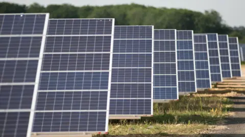 Daniel Leal-Olivas/PA Wire A row of solar panels in a grass field.