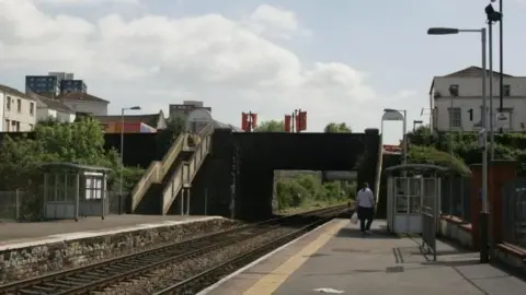 Avalon/Getty Images The photo shows both platforms at Lawrence Hill Station, taken from platform one looking across the tracks towards platform two. In the distance can be seen the steps to platform two, currently the only means of accessing it. A man holding a plastic bag can be seen walking away from the camera on platform one.