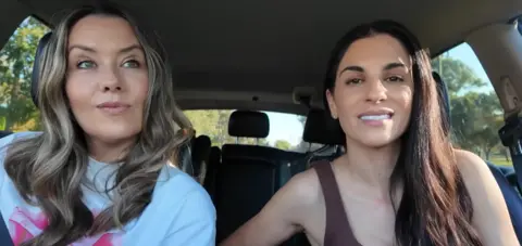 YouTube Empire Family Two women with long hair sit in a car looking at the camera