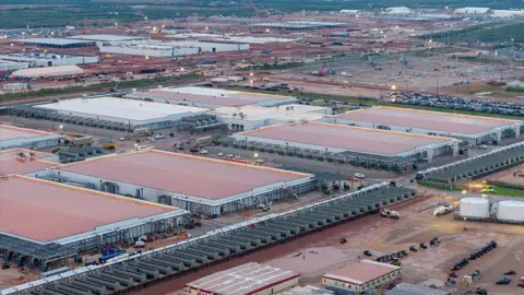 Getty Images Vast buildings being built, with cranes and scaffolding visible over a long landscape.