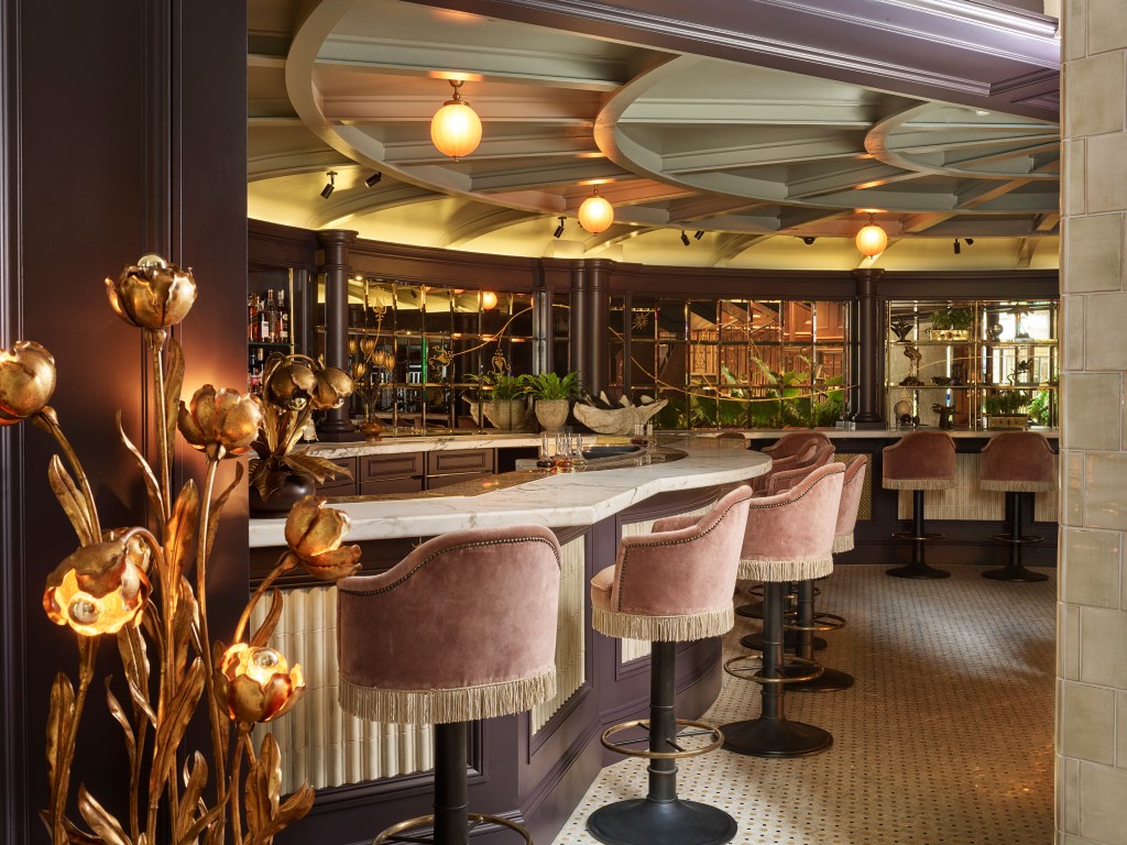 A bar with velvet barstools and gold accents.