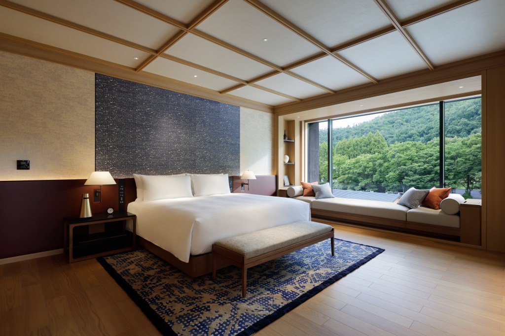 A spacious bedroom with a bench seat in front of a large window.