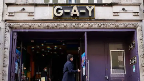 Getty Images The entrance of G-A-Y Bar with purple walls and doors and the venue's name above it. A person can be seen walking past it in the daytime and a person is inside the club's entrance.