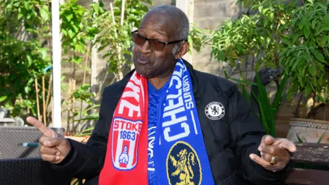 Handout Raymond James wearing a Chelsea Football Club coat and a football scarf
