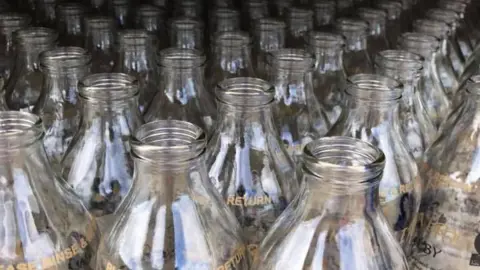 Aalin Dairy The tops of rows and rows of empty clear milk bottles.