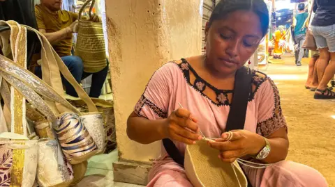 A weaver working as she sits on the floor in the Mercado Nuevo market