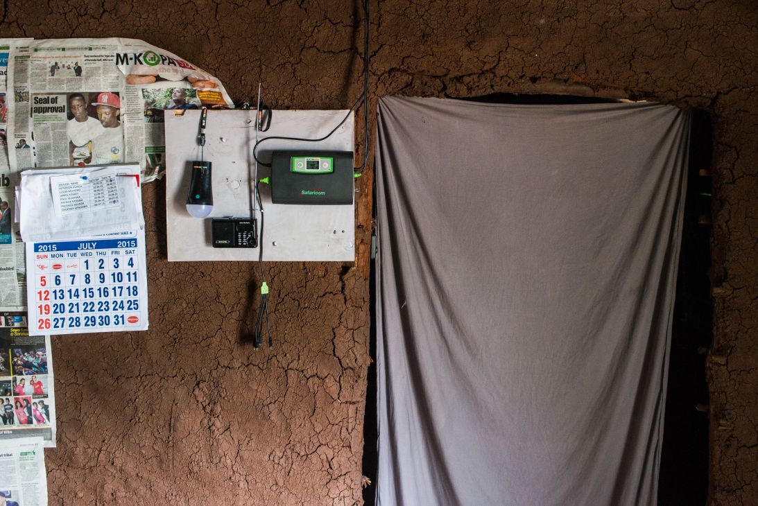 An electric light and control unit on a mud wall in a home powered by M-Kopa solar technology in Ndela village, Kenya.