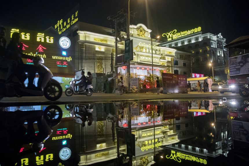 Motorcyclists and the New Mei Gao Mei (New MGM) casino, center, in Sihanoukville, Cambodia, on Friday, March 30, 2018.