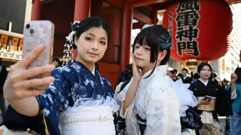 AFP via Getty Images Two Chinese tourists wear kimonos as they visit the Sensoji Temple in the Asakusa district of Tokyo on November 15, 2025. 