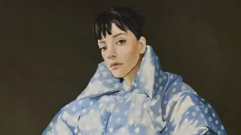 Murray Chalmers PR/PA/BMG Music Artwork on the cover of Lily Allen's new album shows her wearing a padded light blue jacket with white polka dots. She has dark brown hair with a fringe.