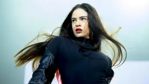 Getty Images Rosalía in a black top, she has long, dark hair