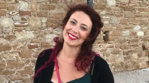 Kat Denisi Kat has red lipstick on and is smiling at the camera in happier times.