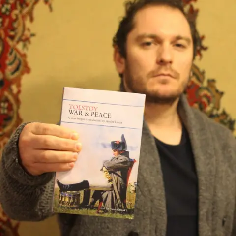 Ander Louis A man holds up a copy of Leo Tolstoy's War & Peace to the camera.