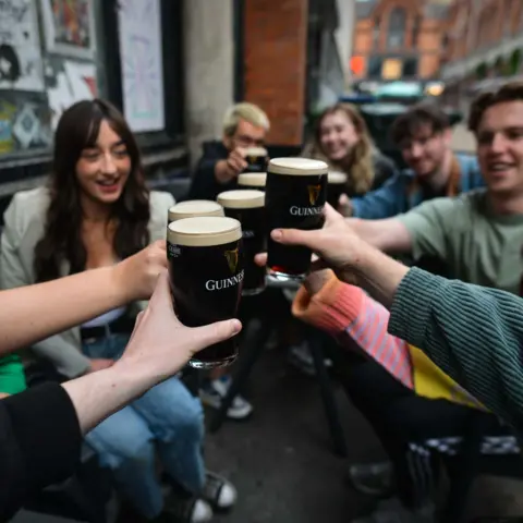 NurPhoto via Getty Images People enjoy drinking Guinness outside a pub in Dublin, Ireland