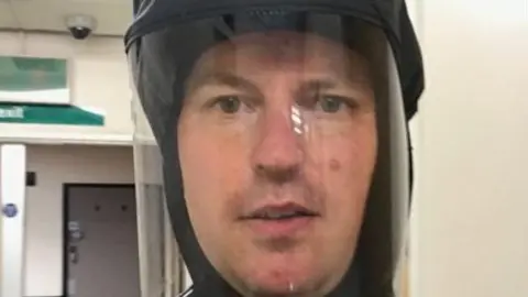 Matt Morgan A man in a protective mask looks at the camera