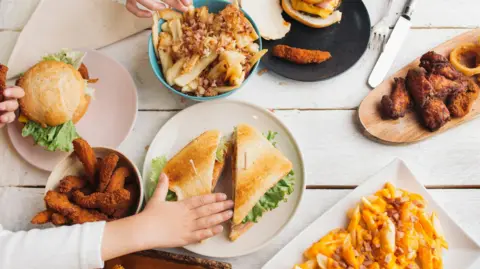 Getty Images A table of ultra-processed foods like chips, chicken nuggets, burgers etc