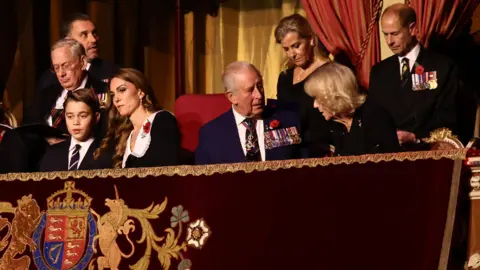 PA Media Prince George, Princess Catherine, King Charles and Queen Camilla are pictured sat in the front row of a royal box. 