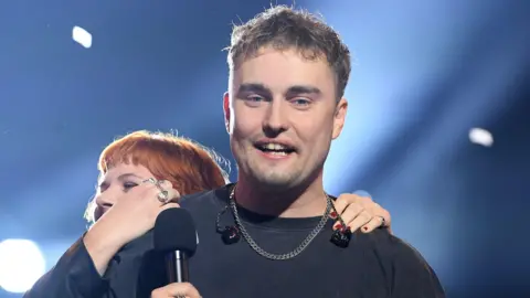 Getty Images Sam Fender is hugged by a bandmate as he wins the Mercury Prize