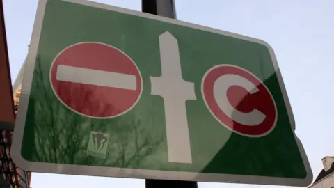A sign shows no entry for drivers going left and a congestion charge for those going right