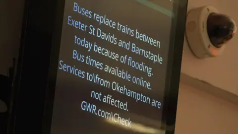 BBC An electronic information sign on the wall of a railway station