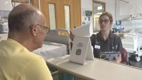 BBC A Dementia Research Nurse turns a flip chart of images for a clinical trial participant to identify.
