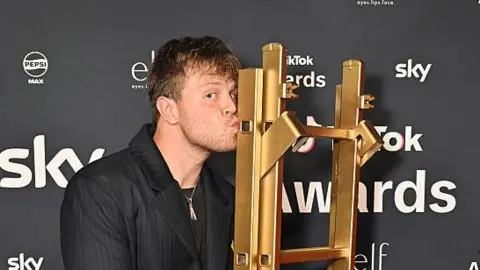 Getty Images Max Klymenko kissing a golden ladder