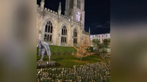 Clatterbridge Cancer Charity Hundreds of steel flowers in the garden of Liverpool's St Luke's Bombed Out Church as the sun sets. 