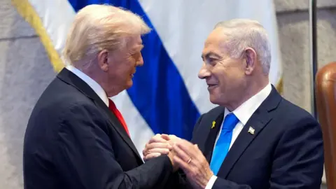 Reuters US President Donald Trump (L) shakes hands with Israeli Prime Minister Benjamin Netanyahu (R) during an address to the Israeli parliament in Jerusalem (13 October 2025)