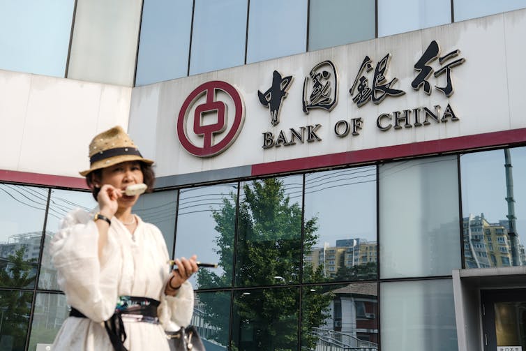 A woman walks outside a Bank of China branch in Beijing, China