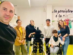 Group photo at a Pisa rehab centre showing clinicians and RoboCT staff standing beside a child wearing the KidGo paediatric exoskeleton during a supervised session.