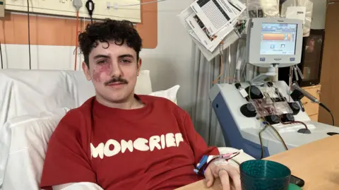 Fin, 19, from Leicestershire, wearing a red T- shirt and wired to the stem cell collection machine in Nottingham 