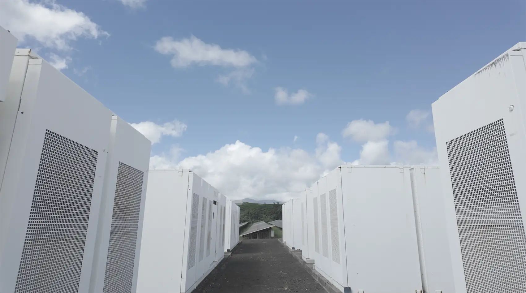 Two rows of batteries under a blue sky with clouds.