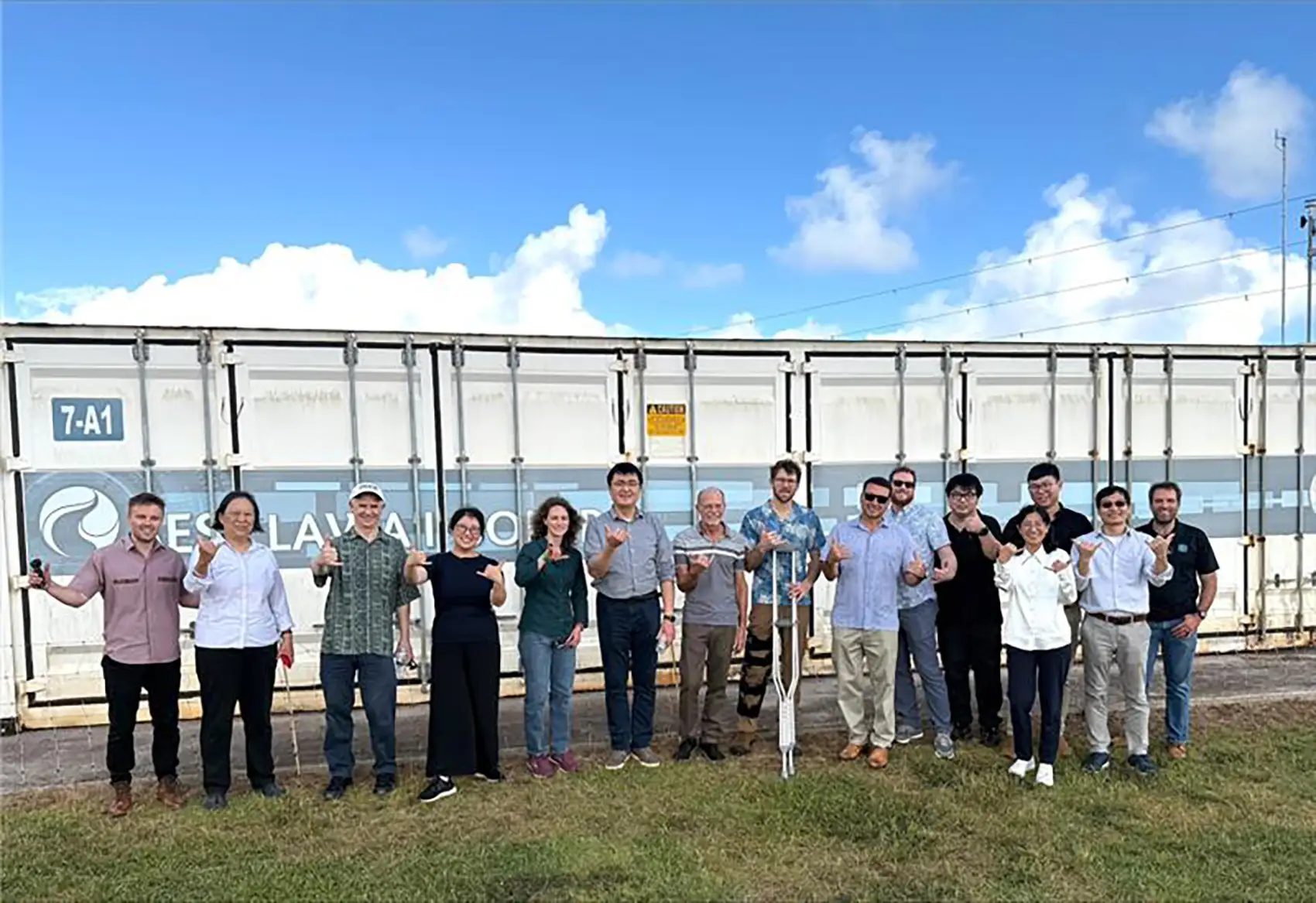 A group of people stand in front of a shipping container.