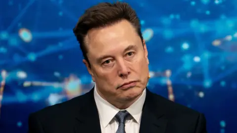 Bloomberg via Getty Images Elon Musk looking off camera in front of a blue background