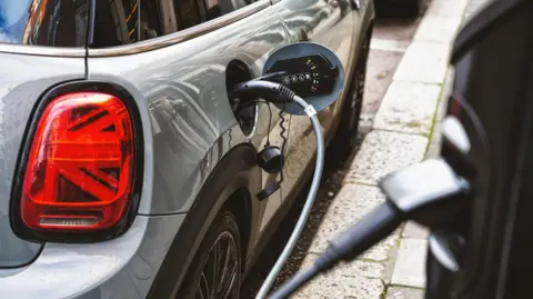 Getty Images A view of a car charging via an on-street electric car charger. 